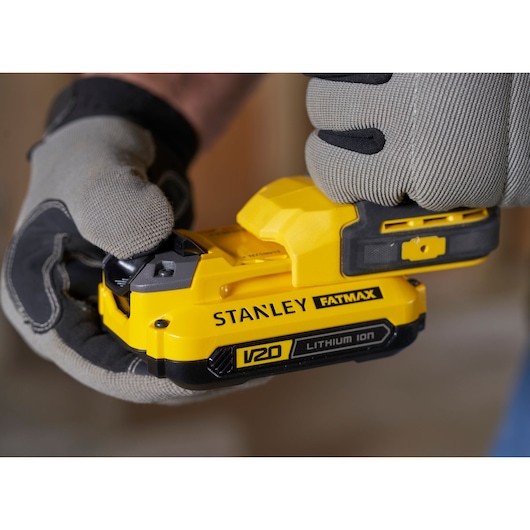 Photo of STANLEY SFMCD710C2K V20 FATMAX lithium ion battery in a gloved hand, close-up view.