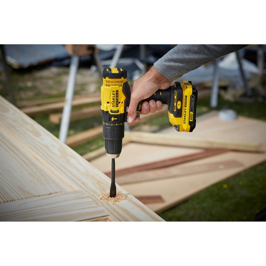 STANLEY SFMCD711D22 cordless drill in use on wood panel, close-up photography outdoors.