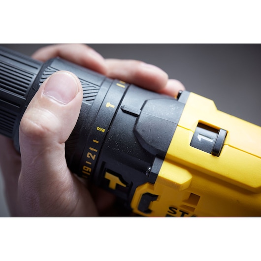 Photo of STANLEY SFMCD711D22 cordless drill, yellow and black, close-up of hand adjusting settings.