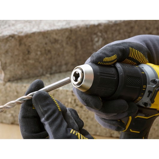 Photo of STANLEY SFMCD715D2K cordless drill held in gloved hands with a drill bit being inserted into the chuck.