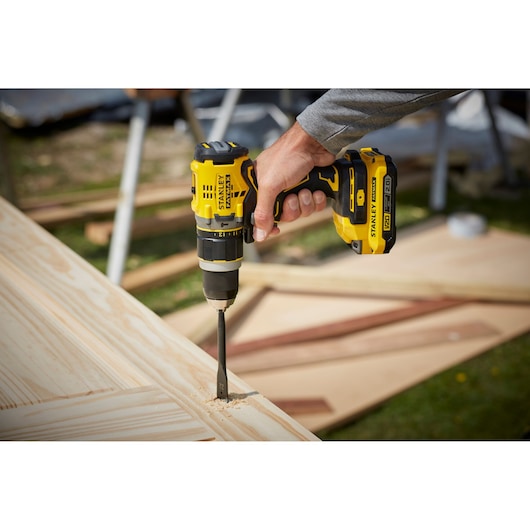 STANLEY SFMCD721D2K cordless drill in use on light wood outdoors, close-up view.