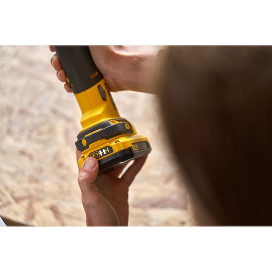 Photo of STANLEY SFMCE500B handheld yellow sander being held on wooden surface.