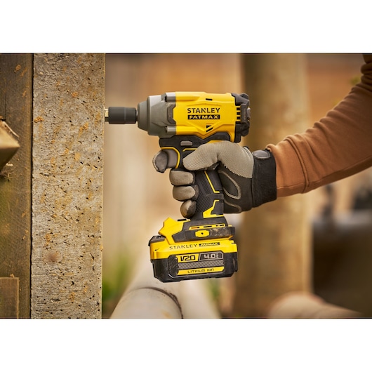 Stanley SFMCF920B cordless impact driver in use, yellow and black design, worker holding tool.