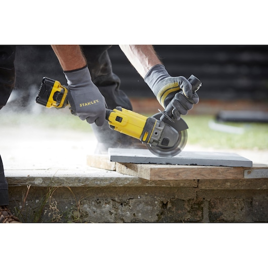 STANLEY SFMCG400M2K cordless angle grinder in use cutting concrete, close-up outdoors.