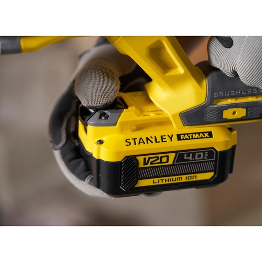 Photo of STANLEY SFMCH900B V20 4.0Ah Lithium Ion battery pack attached to yellow power tool, close-up.