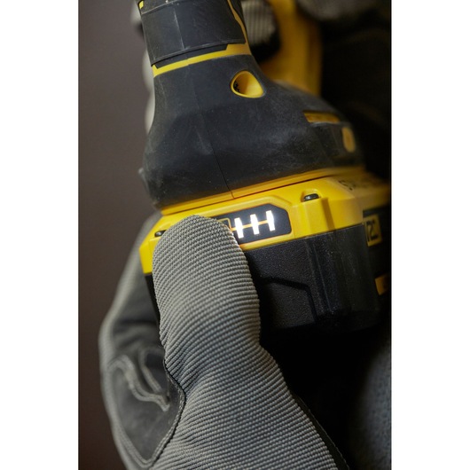 STANLEY SFMCH900B power tool close-up, battery indicator lit, glove pressing button, side angle.