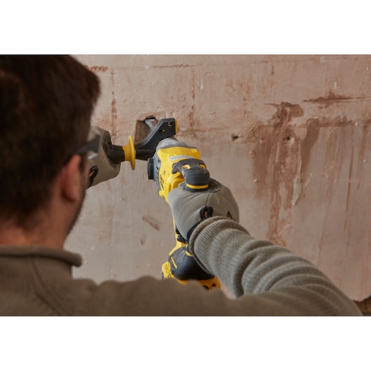 Photo of STANLEY SFMCH900M22 reciprocating saw in use cutting wall, close-up from behind.