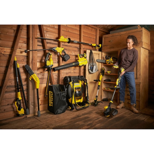 Photo of STANLEY SFMCHT855M1 yard tools lineup, including trimmer, blower, and accessories organized in a wooden shed.