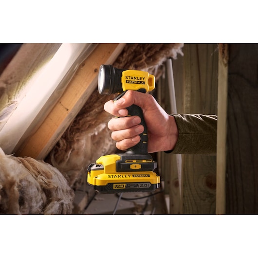 Photo of STANLEY SFMCL020B cordless yellow and black work light held in hand, shown in attic setting.