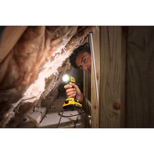 STANLEY SFMCL020B cordless work light used in an attic space, yellow body illuminates insulation.
