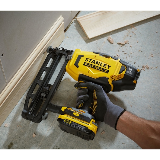 Photo of STANLEY SFMCN616B cordless nail gun in use, yellow and black, close-up angled view.