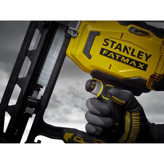 STANLEY SFMCN616B nail gun, close-up side angle, yellow and black design, held by gloved hand.