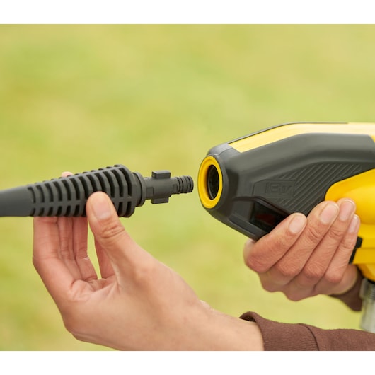 STANLEY SFMCPC93M1 pressure washer nozzle connection close-up, yellow and black tool held by hand.