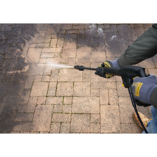 Stanley SFMCPW1500B pressure washer cleaning dirty stone patio, close-up angle.