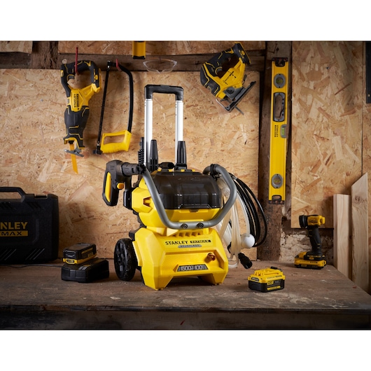 Photo of STANLEY SFMCPW1500B pressure washer on workbench with accessories and tools in workshop setting.