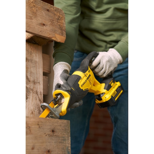 Photo of STANLEY SFMCS300B cordless reciprocating saw cutting wood, yellow and black design, close-up view.