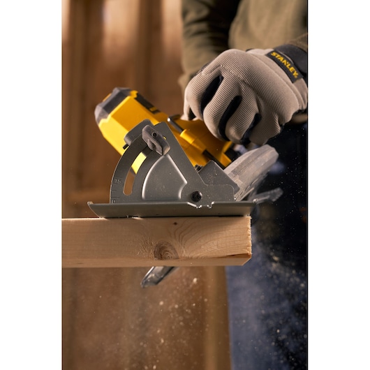 Stanley SFMCS500M2K circular saw photography cutting wood with protective gloves in construction setting.
