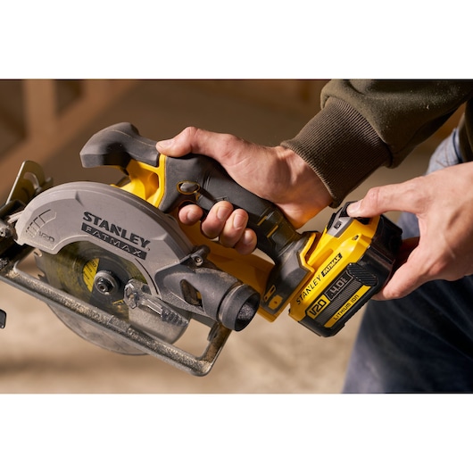 STANLEY SFMCS500M2K cordless circular saw close-up, yellow and black, held by hand, side angle.