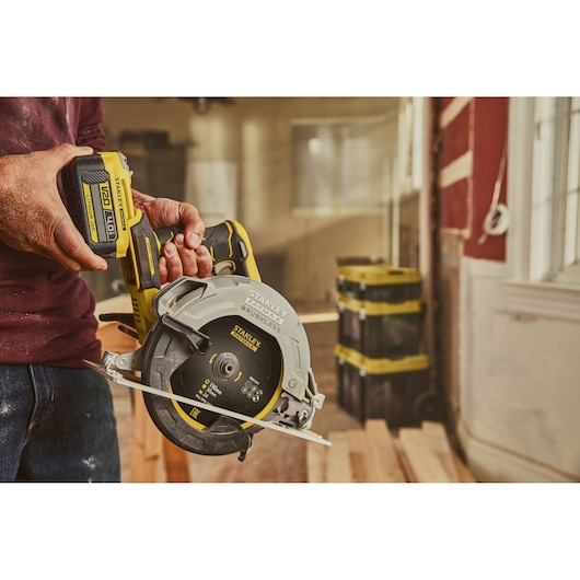 Photo of STANLEY SFMCS550B cordless circular saw in use, yellow and black body, construction setting.