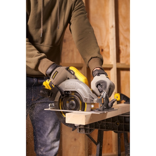 Photo of STANLEY SFMCS550B circular saw in use, cutting wood with dust in workshop setting.