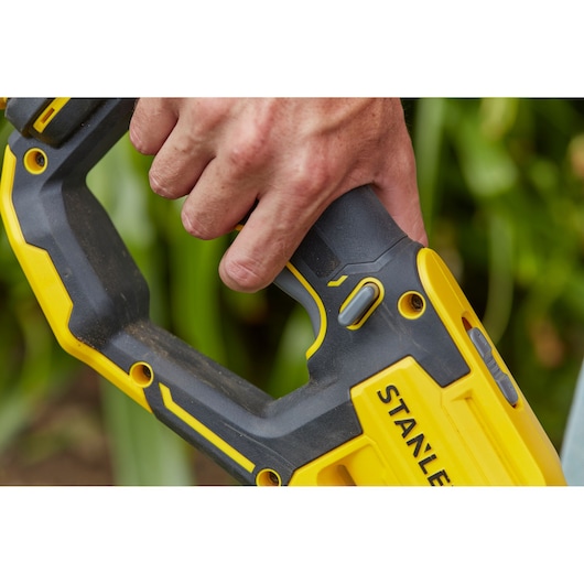 Close-up photo of a hand gripping the handle of a STANLEY SFMCST933M1 cordless power tool with yellow and black design.