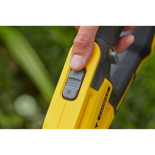STANLEY SFMCST933M1 control switch close-up on yellow tool handle outdoors.