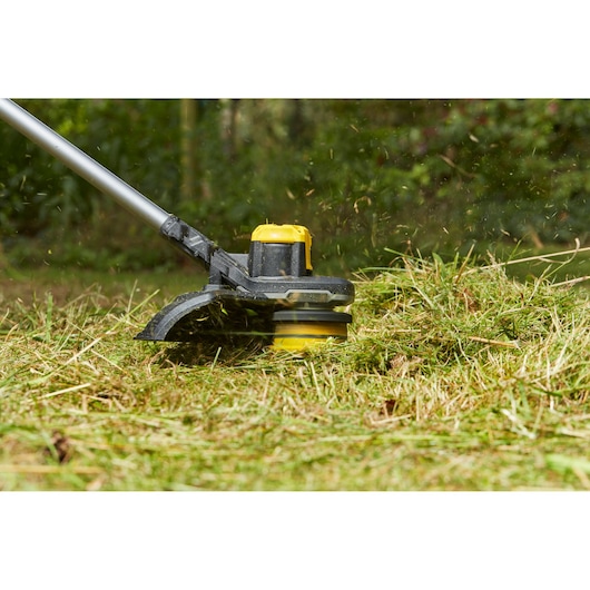 Photo of STANLEY SFMCSTB963B grass trimmer in use cutting grass outdoors.
