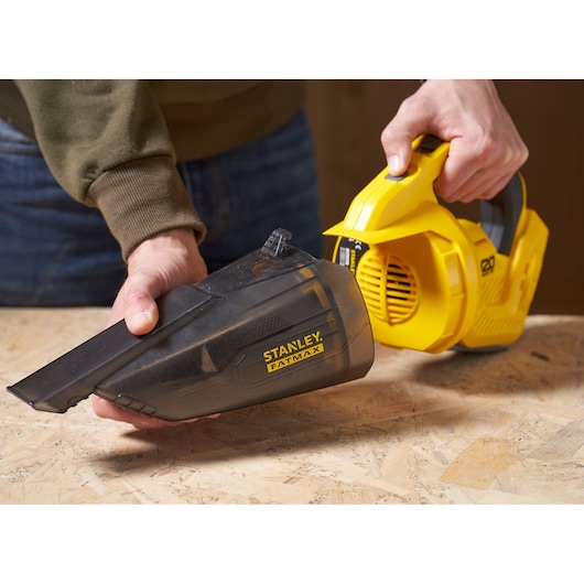 STANLEY SFMCVH001B handheld vacuum cleaner with dust container being removed, photo on wood surface.