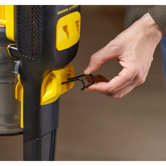 Photo of STANLEY SFMCVS001D1 vacuum cleaner detail, close-up of hand unlocking yellow latch.