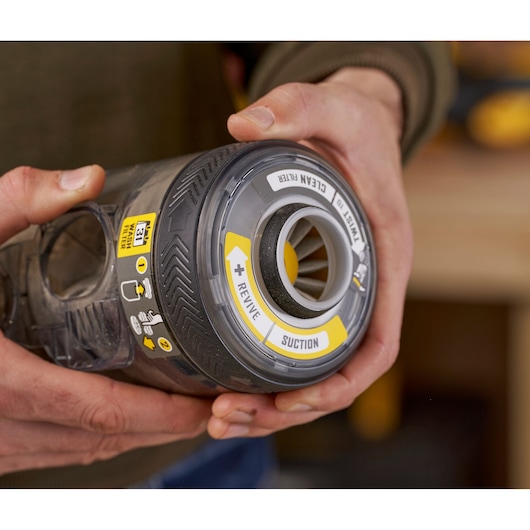 STANLEY SFMCVS001D1 vacuum filter canister close-up, showing yellow REVIVE and SUCTION labels, held in hands.