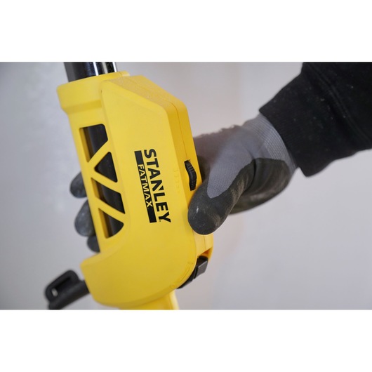 Photo of STANLEY SFMEE500S yellow tool handle with black FATMAX logo, gripped by gloved hand, close-up view.