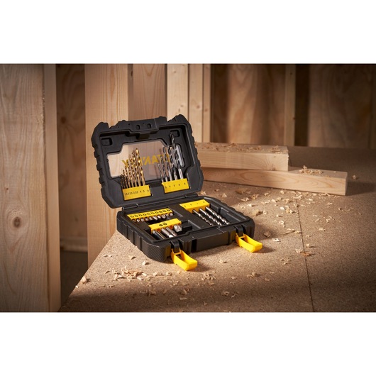 STANLEY drill and bit set in black and yellow case on a wooden workbench, surrounded by wood shavings.