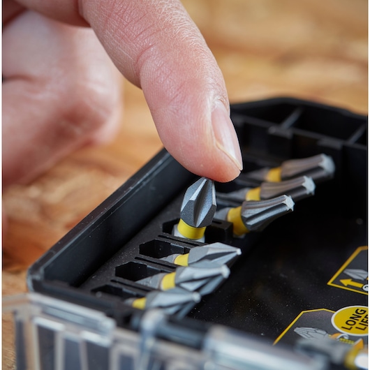 STANLEY STA88558 screwdriver bit set, close-up of finger selecting a grey and yellow bit from case.