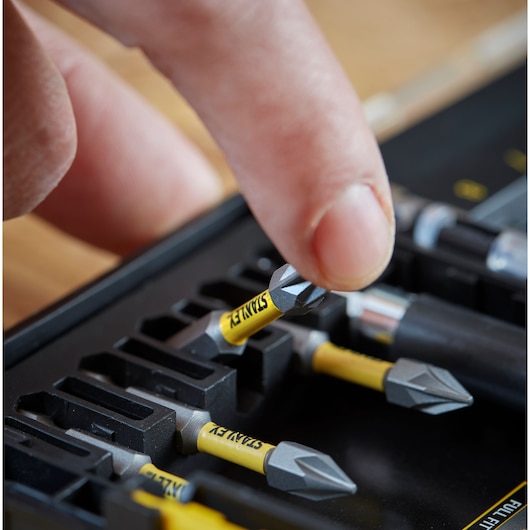 STANLEY STA88558 screwdriver bits in yellow and black case, close-up of hand picking one bit.