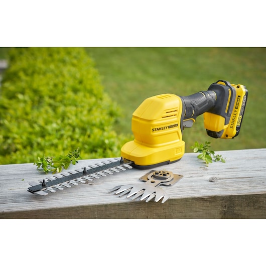 STANLEY STCSS20D1 cordless shrub shear and grass trimmer in yellow shown outdoors with attachments.
