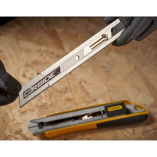 STANLEY STHT0-11825 utility knife with blade extended, yellow and black handle, close-up on wood surface.