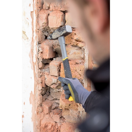 STANLEY STHT0-51910 hammer with black and yellow handle used on damaged brick wall.