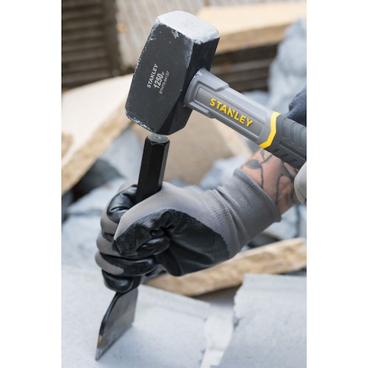 STANLEY STHT0-54127 sledge hammer being used with a chisel on stone, close-up view.