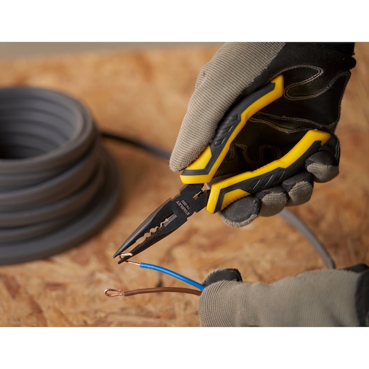 STANLEY STHT0-74363 pliers with yellow and black handle stripping electrical wires, close-up.