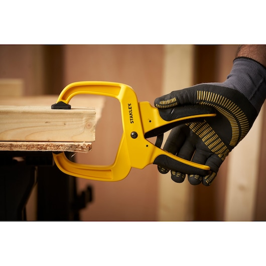 STANLEY STHT0-83200 clamp holding wooden boards, gloved hand operating, product in workshop use.
