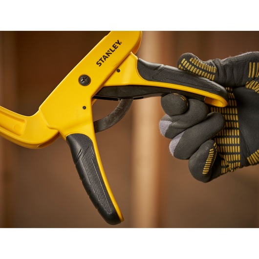 Photo of STANLEY STHT0-83200 one-handed clamp held by a gloved hand, close-up view.