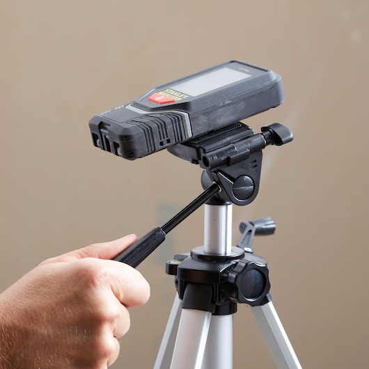 STANLEY STHT1-77142 laser distance measurer on tripod, side angle, hand adjusting handle.