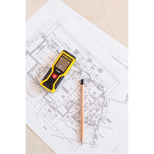 STANLEY STHT1-77409 laser distance measurer with pencil on architectural plan, top view, photography product.