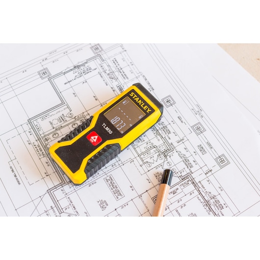 STANLEY STHT1-77409 laser distance measurer on architectural blueprint with pencil.