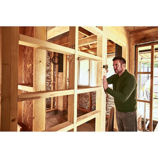 STANLEY STHT1-77409 laser level used by worker in wooden frame construction site.