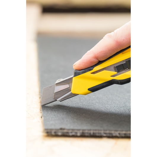 STANLEY STHT10270-0 utility knife cutting black material, close-up side view.