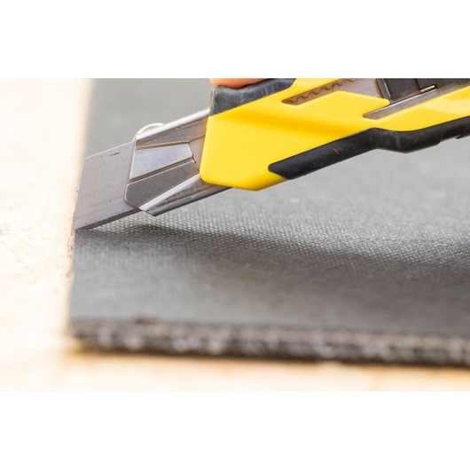 STANLEY STHT10270-0 utility knife with yellow handle cutting black material, close-up photography.