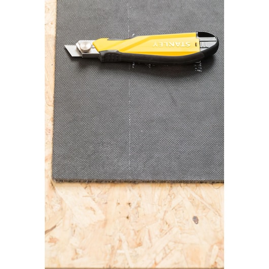 STANLEY STHT10270-0 utility knife on a sheet material, top view, yellow and black handle.