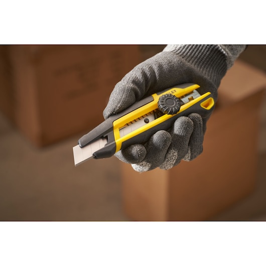 STANLEY STHT10500-0 utility knife with yellow and black handle held in gloved hand, side angle.