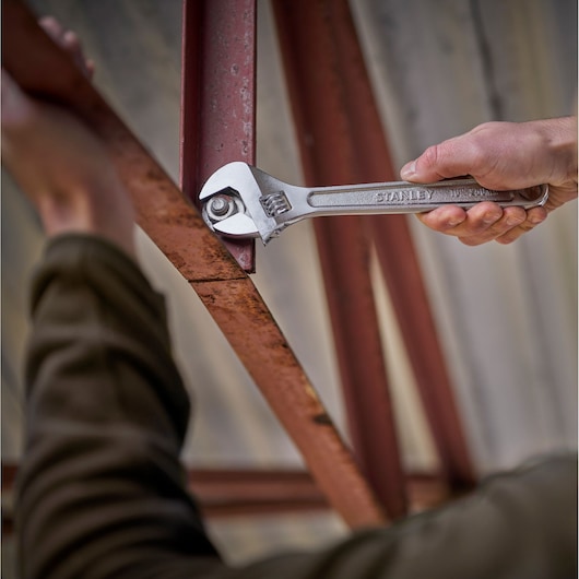 Photography of STANLEY STHT13156-0 adjustable wrench tightening a bolt on a rusted metal beam.